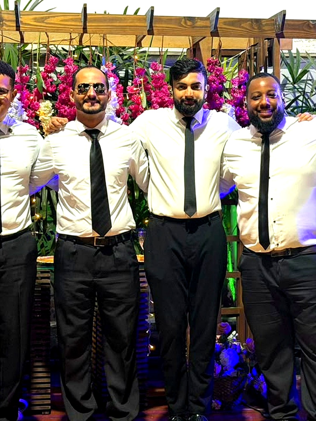 Os seis integrantes da Banda Marvin sorrindo no palco iluminado de um evento